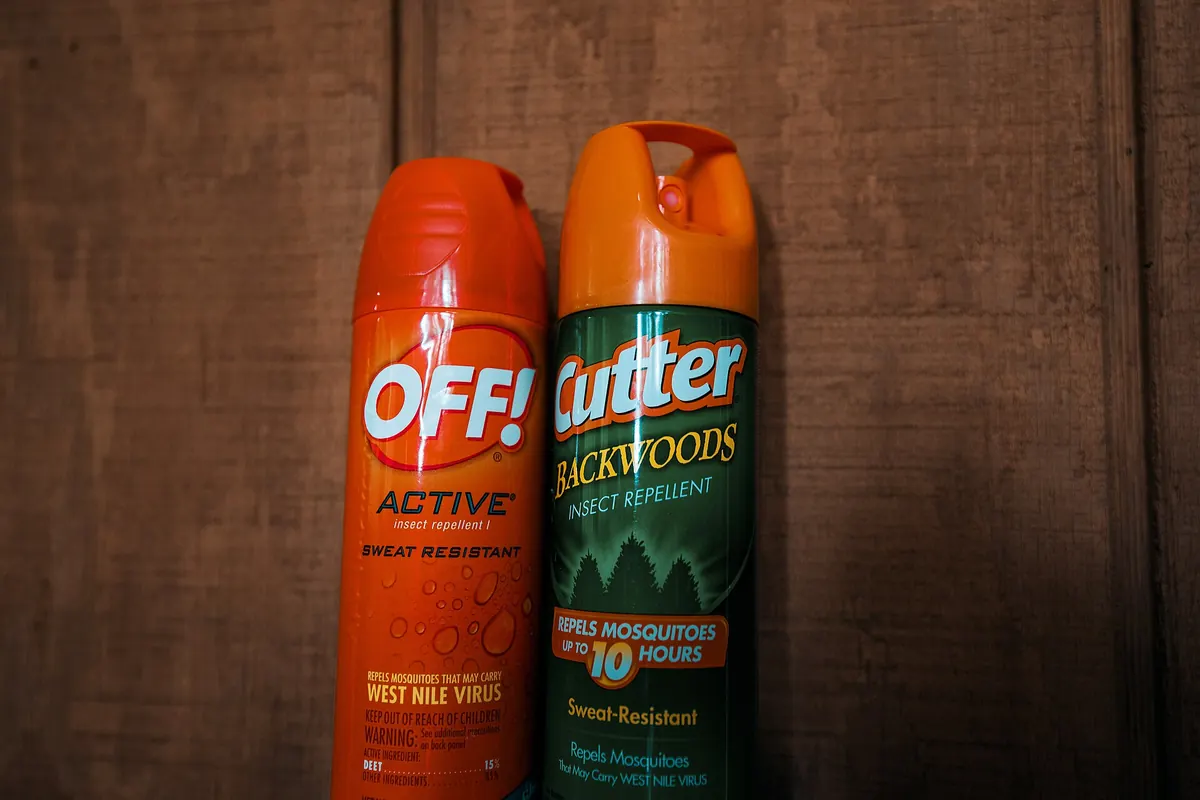 Off and Cutter insect repellent spray cans, one orange and one green, on a wooden surface