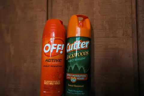 Off and Cutter insect repellent spray cans, one orange and one green, on a wooden surface
