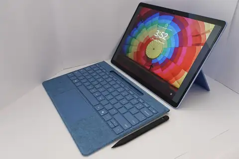 A laptop-style computer with a blue keyboard cover and a stylus pen on a white surface