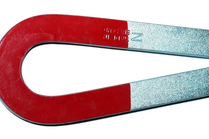 Red horseshoe magnet with pale silver ends on a white background