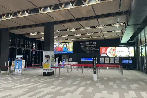 Empty security check area at Kumamoto Airport in Japan with rope barriers, pillars and signage