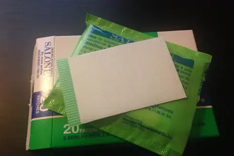 A Salonpas pain relief patch box with a green foil packet and one white patch on top