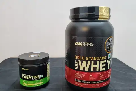 A tub of Optimum Nutrition whey protein powder next to a smaller container of creatine powder