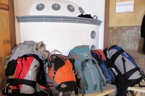 Four hiking backpacks of different colors lined up on a wooden bench