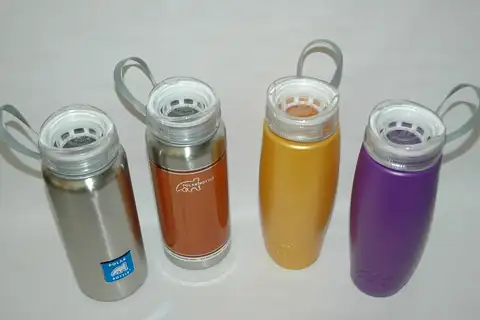Four Polar Bottle metal water bottles in different colors with loop-handle lids, lined up on a white background