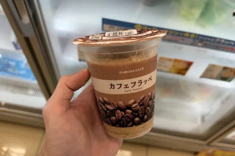A FAMIMA CAFE Cafe Frappe cup held in front of the freezer at a FamilyMart in Tokyo on 20 October 2026
