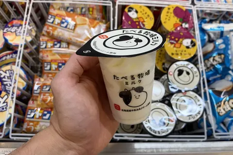 A cup of Akagi Taberu Bokujo Milk ice cream held over the freezer at a FamilyMart in Tokyo on 20 October 2026
