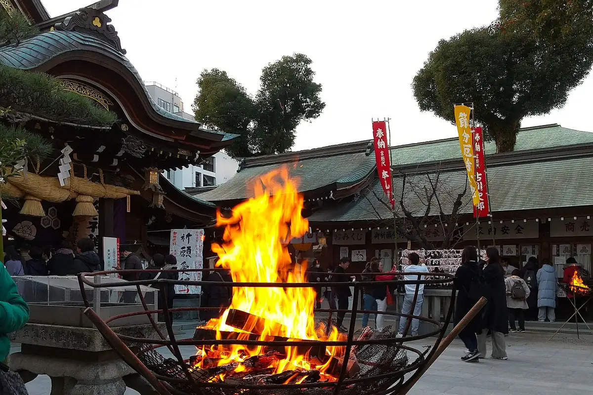 櫛田神社の節分大祭で金属のかごに燃える大きな火、周りに人々と赤い旗
