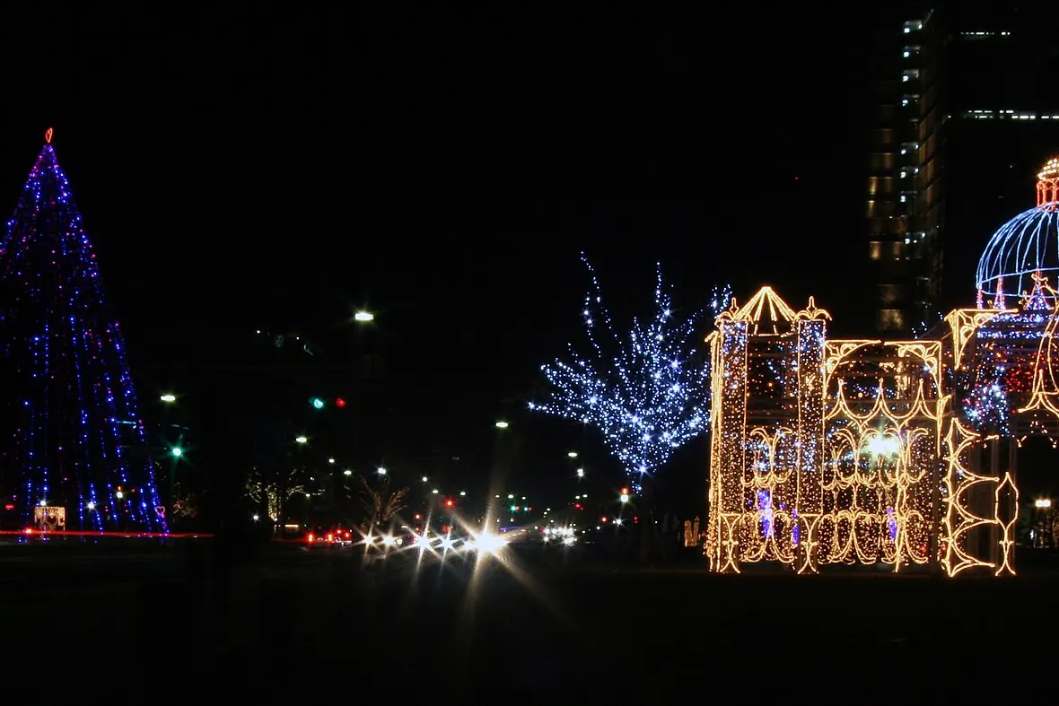 A cone-shaped tree in blue lights and a golden light structure on Peace Boulevard in Hiroshima at night