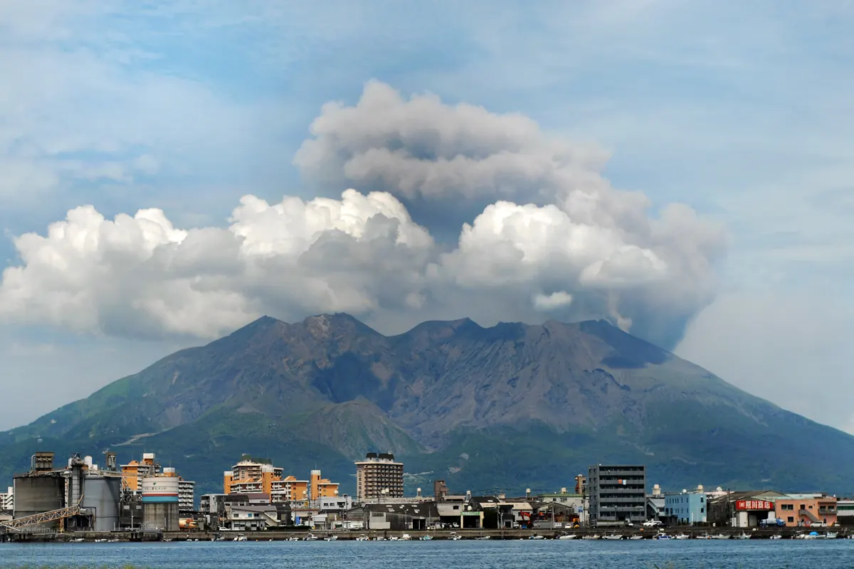 鹿児島湾の上に噴煙を上げる桜島、手前に広がる市街の景観