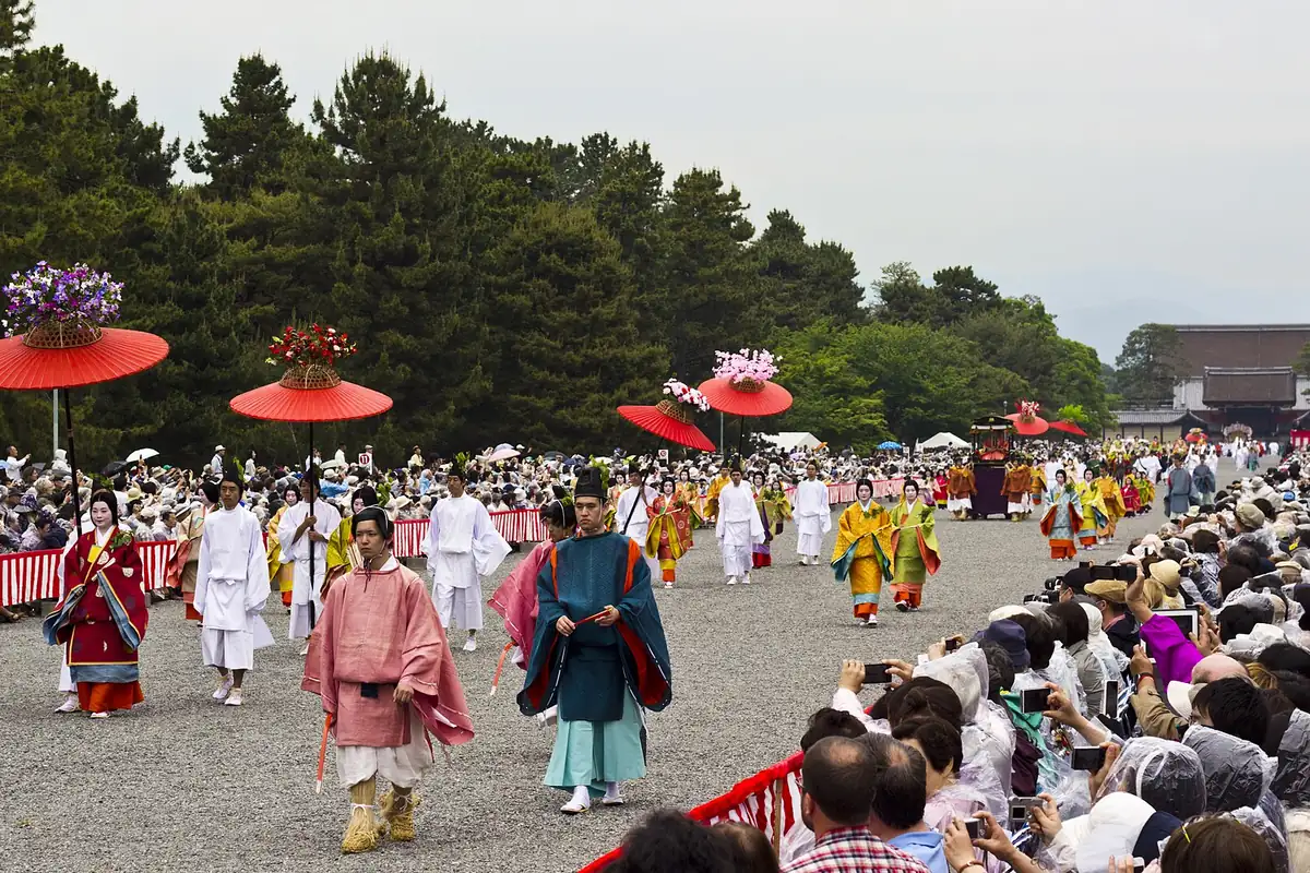 Aoi Matsuri procession with costumed participants and red parasols decorated with flowers in Kyoto