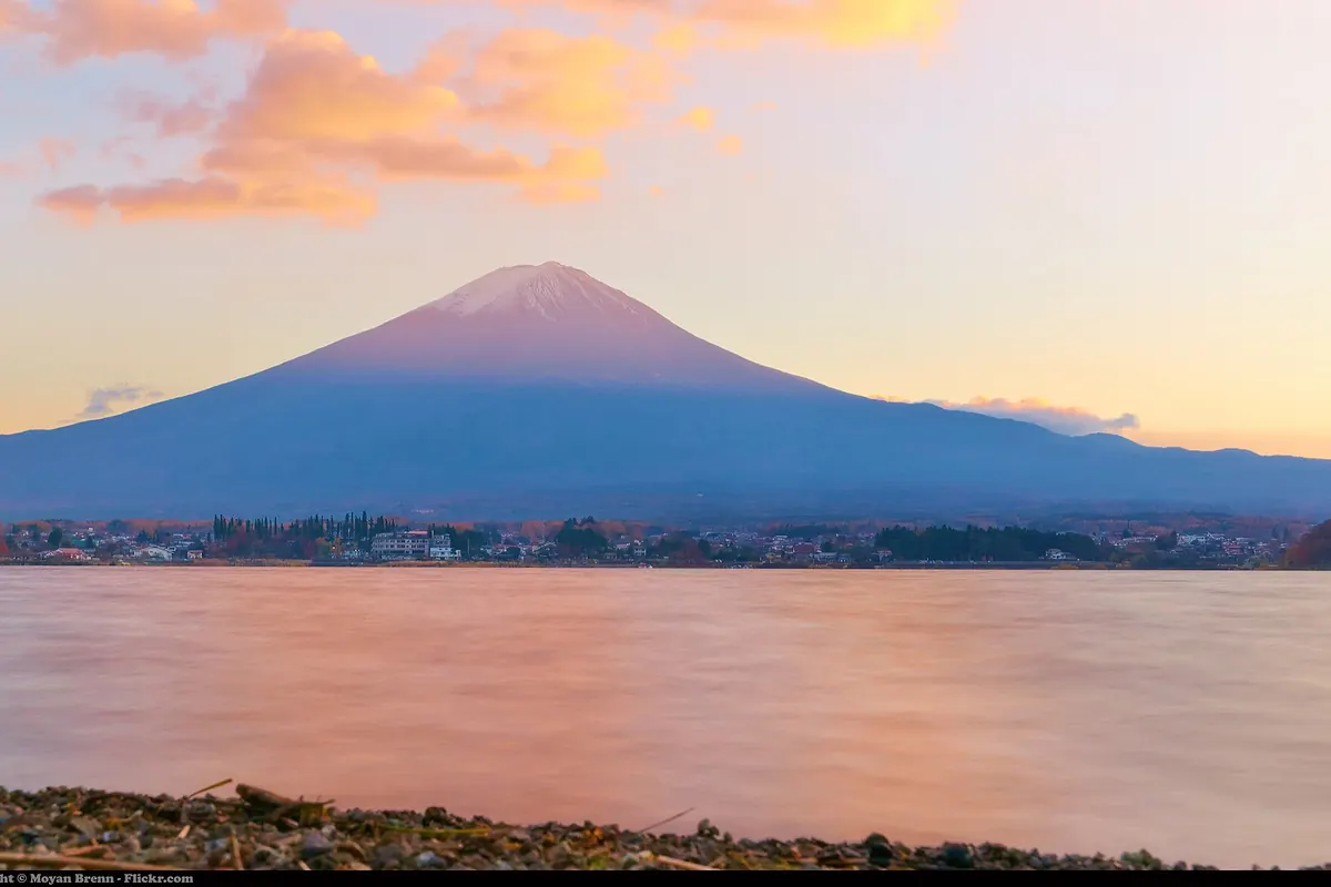 Mount Fuji at sunset across Lake Kawaguchiko, its snowy summit tinged pink above a lakeside town