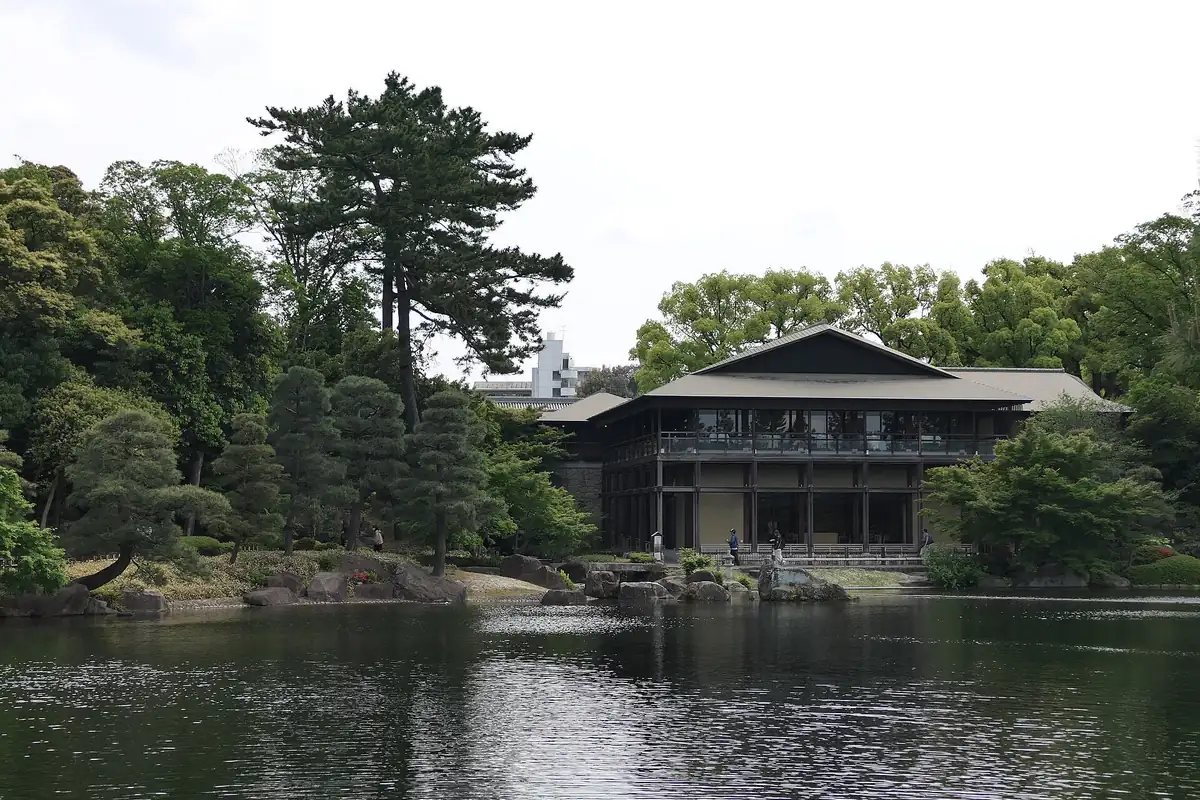 Ryusen Lake at Tokugawa-en garden in Nagoya, with green trees and a traditional wooden building on the far shore