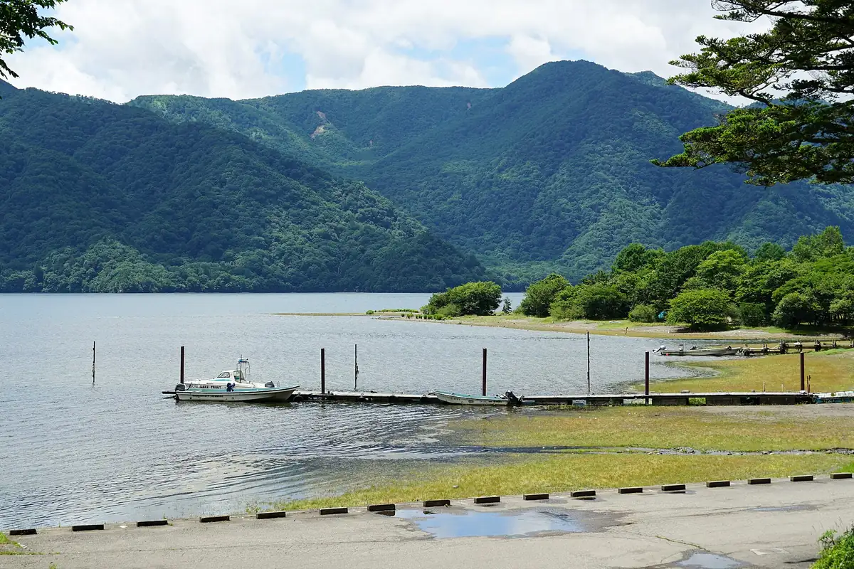 菖蒲ヶ浜から見た夏の日光・中禅寺湖。緑の山々と小さな桟橋とボート