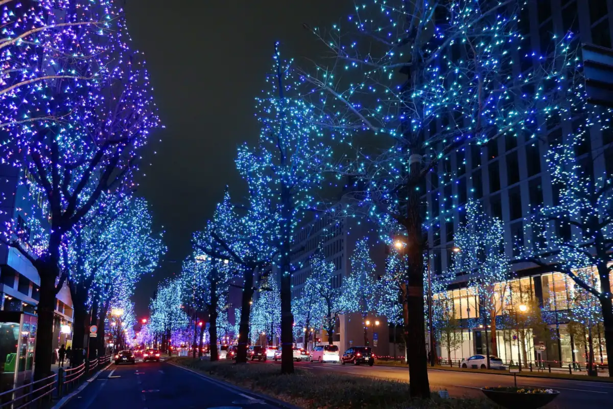 Blue and purple illumination lights covering a row of trees along Osaka's Midosuji avenue at night