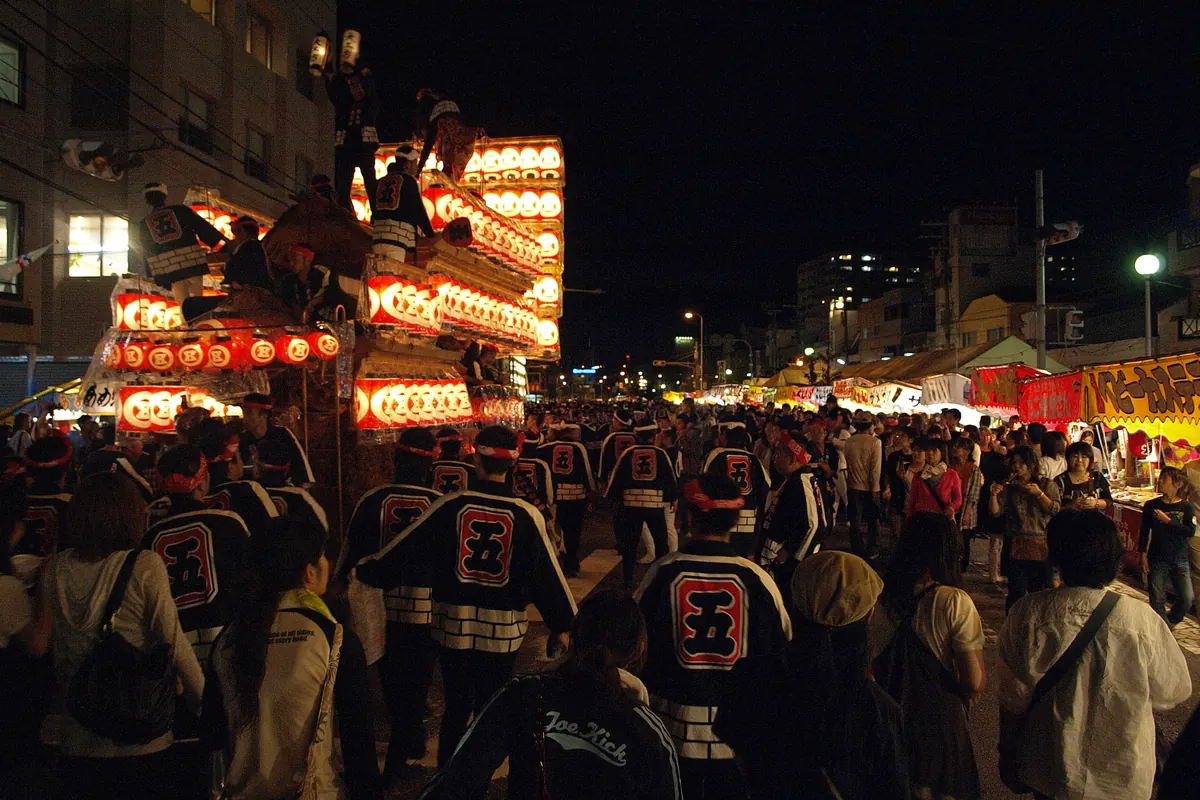 岸和田だんじり祭の夜、提灯に照らされただんじりを囲む黒い法被姿の男たち