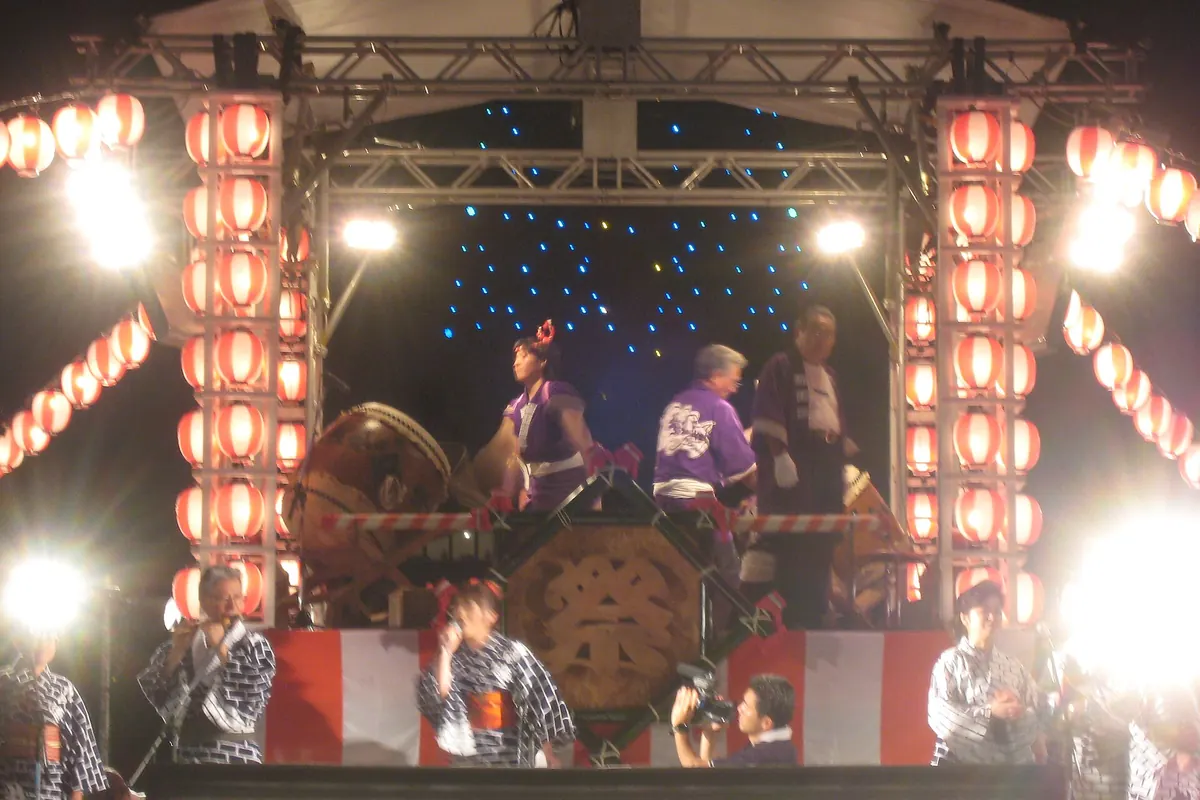 札幌夏日祭典的夜晚，紅燈籠排列的舞台上大太鼓旁的表演者