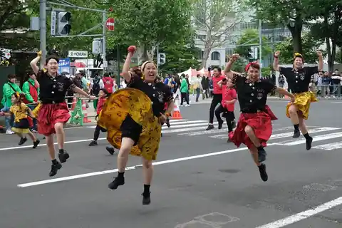 삿포로 오도리 공원의 요사코이 소란 축제에서 뛰어오르는, 검은 상의에 빨강과 노란 치마 차림의 댄서들
