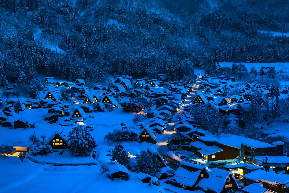 夜晚自高處俯瞰白川鄉，積雪合掌造房屋的窗戶點著燈