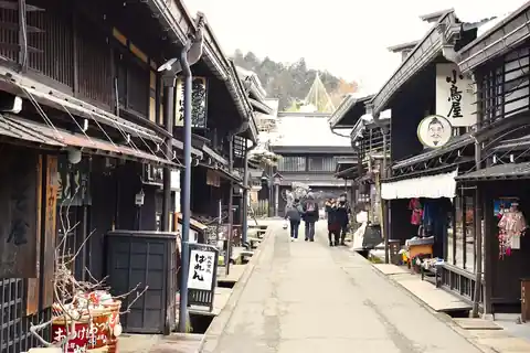 다카야마 옛 거리에 늘어선 어두운 목조 가옥과 상점 간판, 걸어가는 몇 명의 사람들