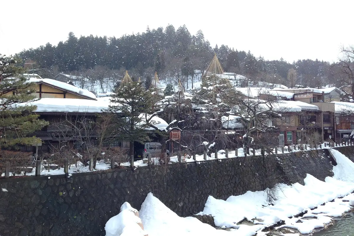 Snow-covered houses above a stone riverbank in Takayama