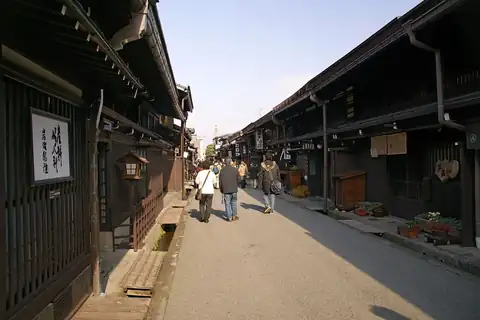 다카야마 산마치에 늘어선 어두운 목조 마치야 거리를 걷는 몇몇 사람들