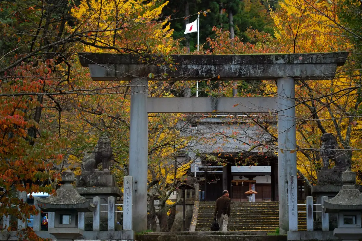 Stone torii gate of Hida Gokoku Shrine in Takayama, with stone steps and yellow autumn trees around it
