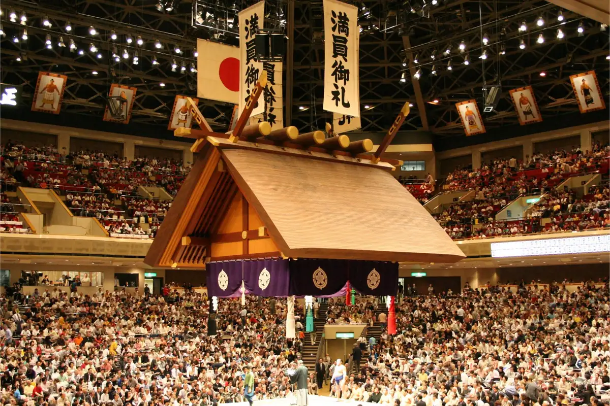 Packed seats around the sumo ring under the hanging shrine roof inside Ryogoku Kokugikan in Tokyo during a tournament