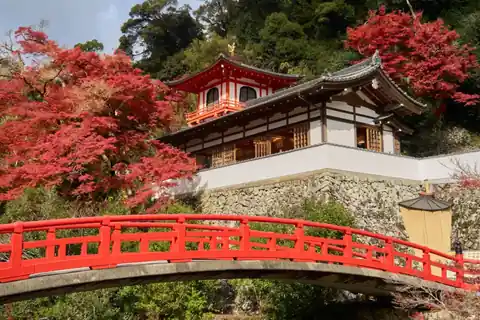 Red arched bridge and a traditional temple building surrounded by red autumn maple leaves at Minoh, Osaka
