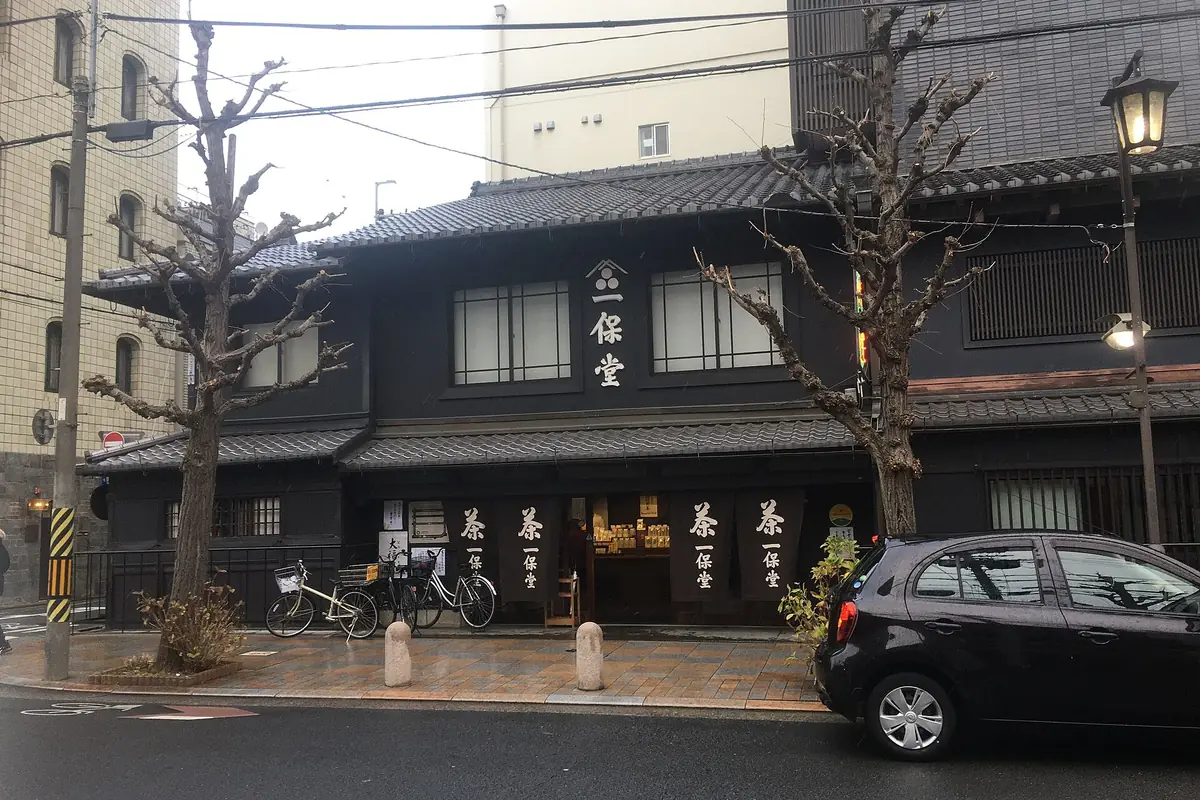 The black wooden front of Ippodo Tea's main store in Kyoto, with noren curtains reading 茶 and 一保堂, bicycles parked outside