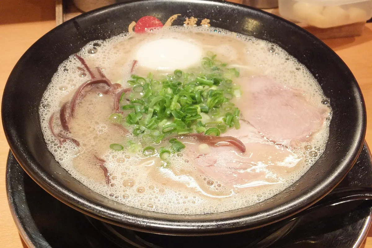 Bowl of Hakata Ikkousha tonkotsu ramen with chopped green onions, pork slices, red pickled ginger, and a soft-boiled egg