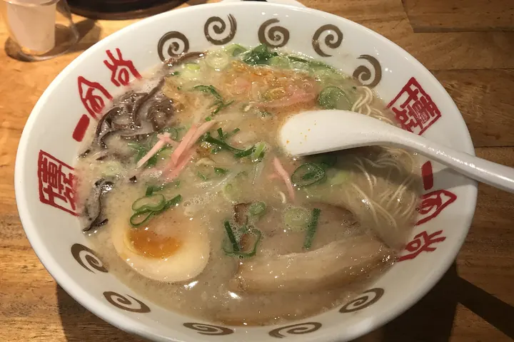 Bowl of Hakata tonkotsu ramen with thin noodles, cloudy broth, pork slices, red pickled ginger, and a soft-boiled egg