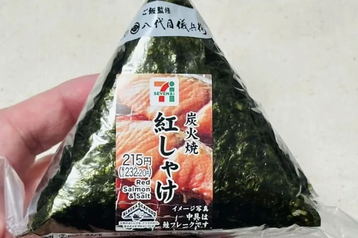 A charcoal-grilled red salmon onigiri from 7-Eleven; the label reads 215 yen