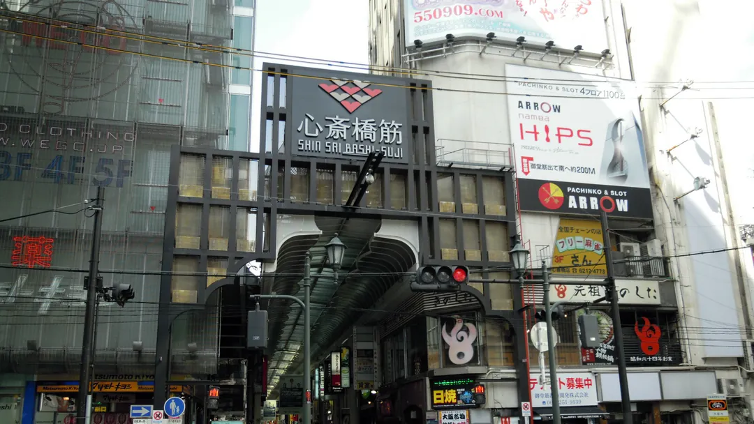 大阪の心斎橋筋商店街の入口で、「心斎橋筋」の看板を掲げたアーケードの門と両側のビルの写真