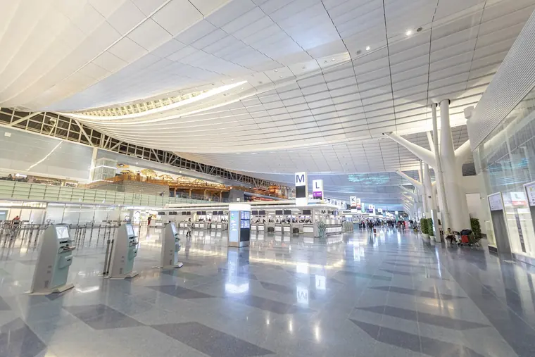 The bright, nearly empty departure hall of Haneda Airport Terminal 3, with self check-in kiosks.