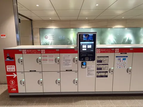 A row of coin lockers around a central payment terminal at Osaka Station.