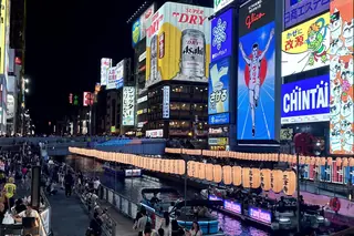 The Dotonbori canal in Osaka at night, with the Glico running man sign, giant billboards and crowds along the water.