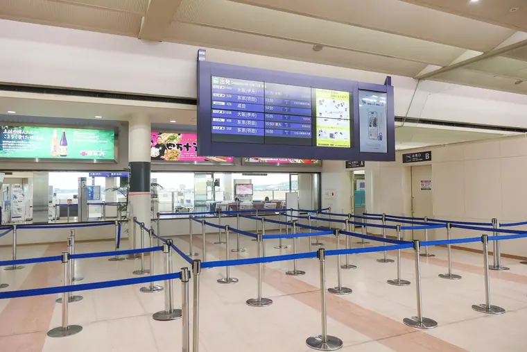 Empty queue lanes in front of the security check at Kochi Airport, below a flight information screen.