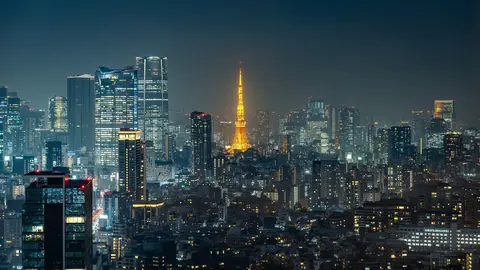 Tokyo Tower glowing orange among the office towers of central Tokyo at night.
