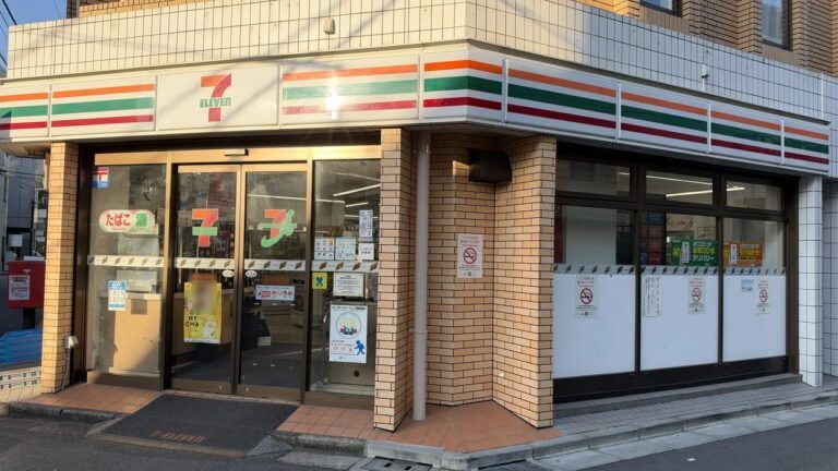 東京のセブン-イレブンの店の正面。入口の上に緑・オレンジ・赤の帯がある