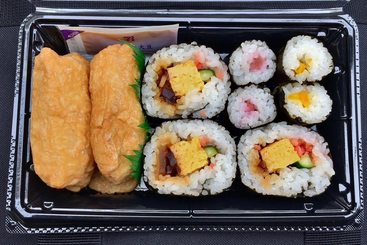 日本7-Eleven的助六寿司套装，塑料盒里装着稻荷寿司和寿司卷