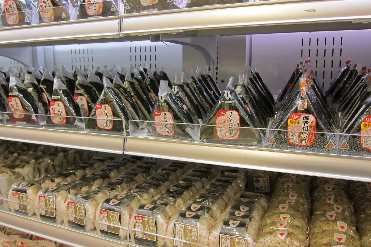 Shelves of triangular onigiri rice balls wrapped in nori with Japanese price and flavor labels