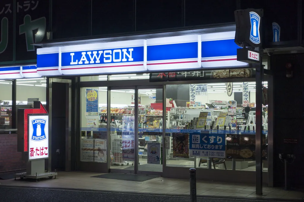 Illuminated Lawson convenience store storefront at night with blue and white signage and glass entrance doors