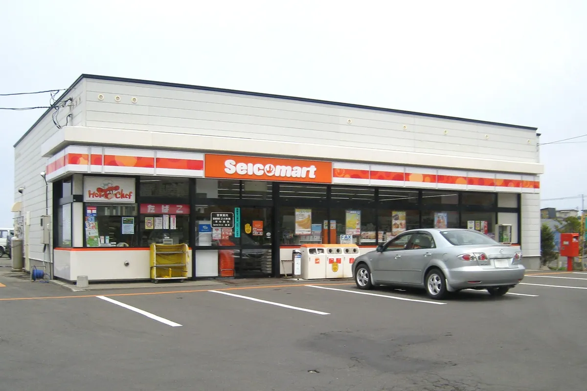 Seicomart convenience store building with orange signage and a car parked in front