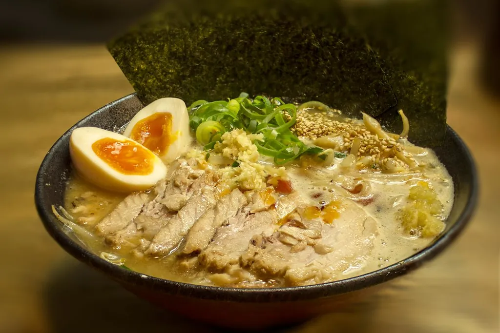 A bowl of miso ramen with sliced pork, a halved soft-boiled egg, green onions, garlic and a sheet of nori in Tokyo