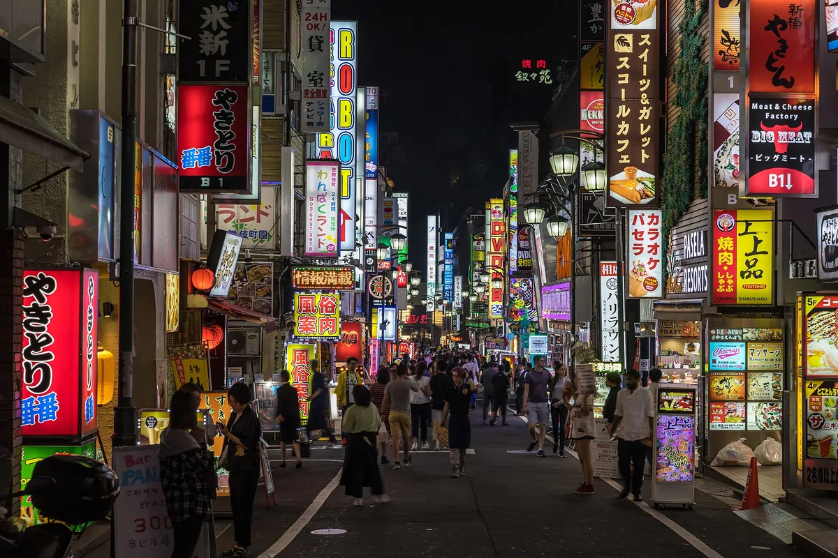 Colorful neon signs covering buildings above a crowded street in Kabukicho, Shinjuku, Tokyo at night
