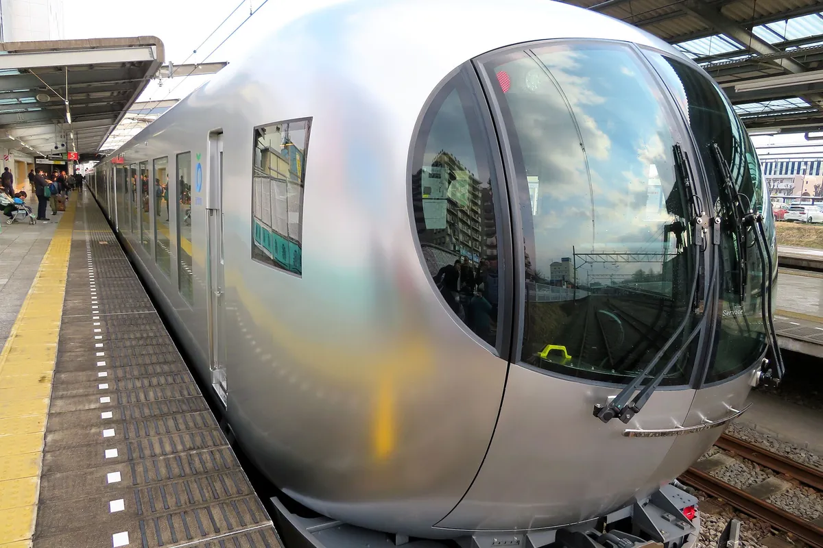 Silver Seibu Railway Laview limited express train with a large round front window at a station platform