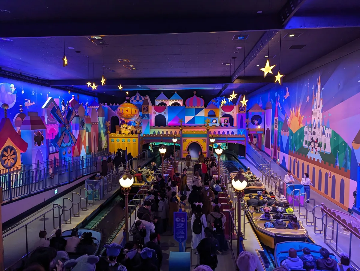 Boats at the loading area of it's a small world under its colorful mural