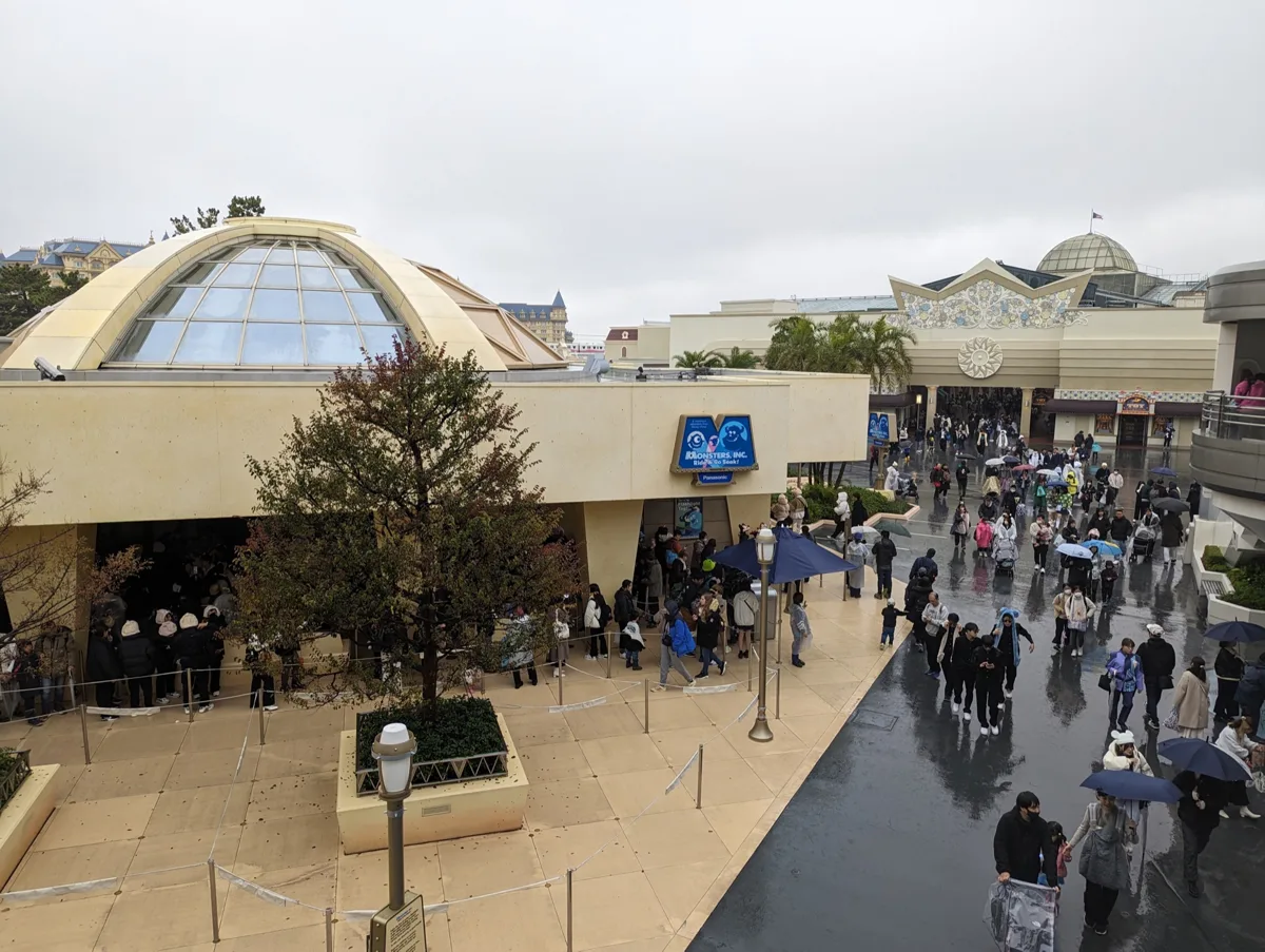 雨の日、モンスターズ・インク“ライド＆ゴーシーク！”の建物の外で並ぶゲストたち