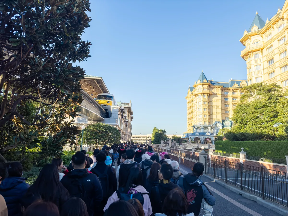 Guests walking in a long line along the path by the Tokyo Disneyland Hotel before the park opens, in 2023
